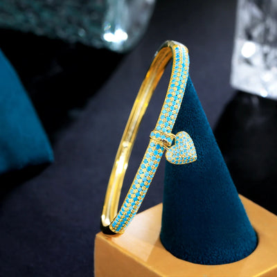 Gold-tone bangle with heart charm and blue cubic zirconia for women